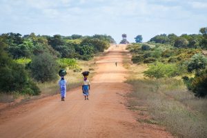 African women walking down the road carrying items on their heads 