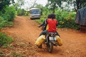 people riding a motorbike along a dirt road in Uganda