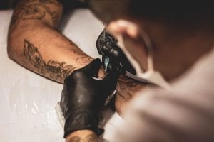 tattoo artist working on a mans arm
