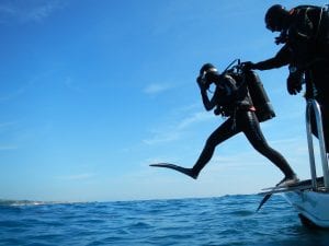 Diver stepping off boat in to the sea