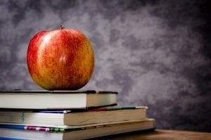 A red apple on top of reading books. The perfect snack