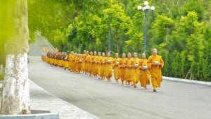 a long line of Buddhist Monks, walking down the road in Vietnam