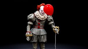 scary clown holding a red balloon