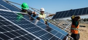 Builders putting solar panels on a roof