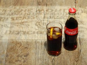 Coke bottle and glass of coke with ice and lemon