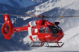 Red and white emergency helicopter, flying through the snowy mountains
