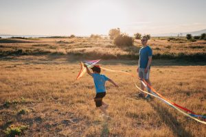 a child flying a kite on a sunny and windy day