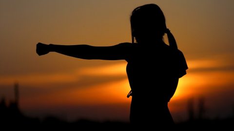 woman practicing karate with a sunset background