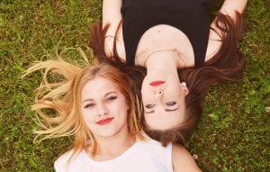 two young women lying on the grass together