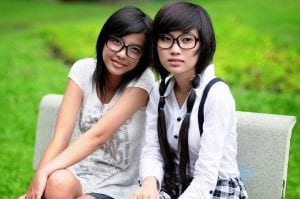 two asian girls on a park bench