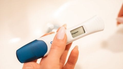 Hand holding positive pregnancy test