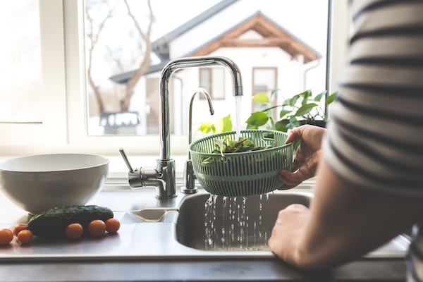 Woman washing lettuce over sink