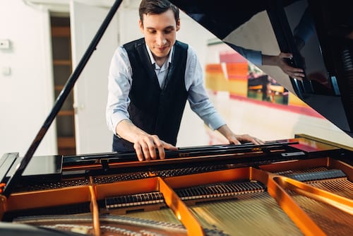 Male pianist sets the grand piano before performance.