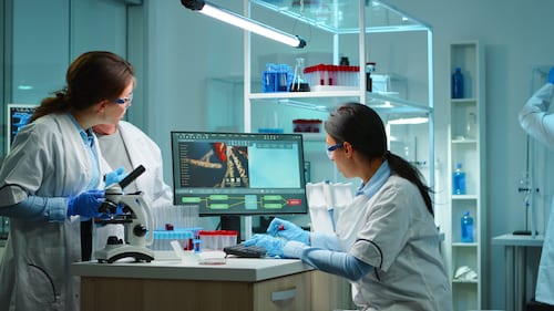 Team of doctors studying DNA mutation, chemist checking tests from tubes while nurses taking notes on notebook and pc. Scientists examining virus evolution using high tech for vaccine development.