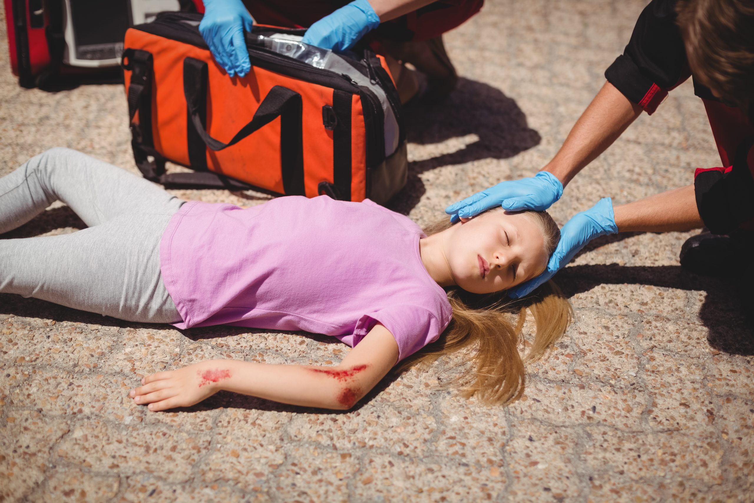 Paramedics examining injured girl on street